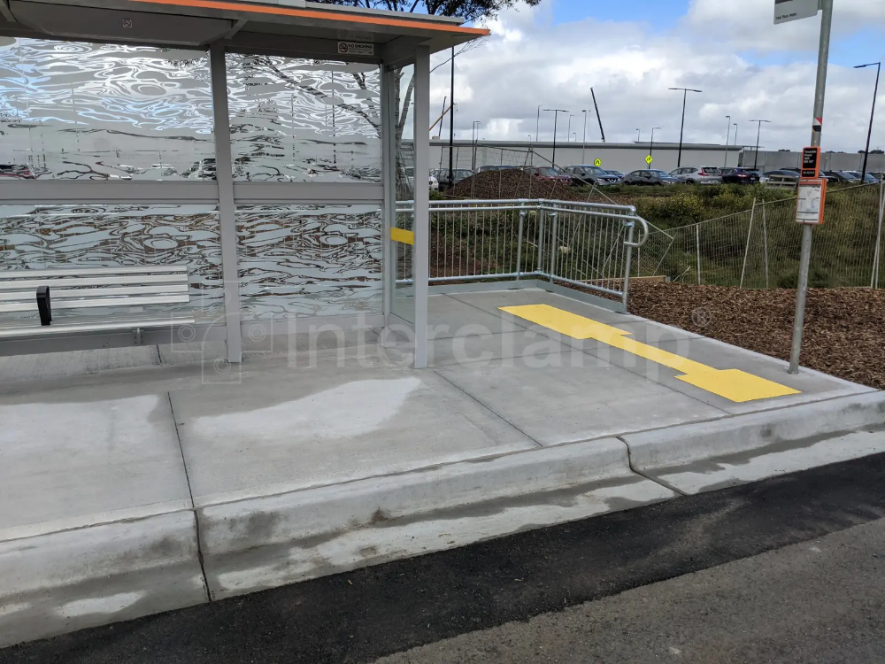 Bus stop equipped with Interclamp pedestrian barriers and DDA assist rail, enhancing safety and accessibility for all commuters.